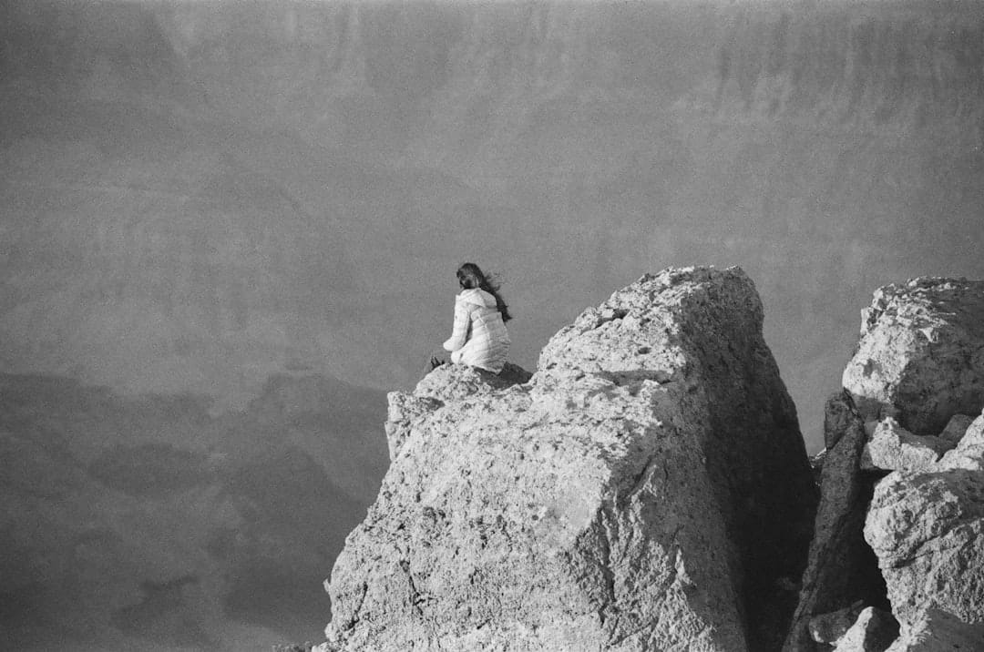 A woman sitting on top of a large rock