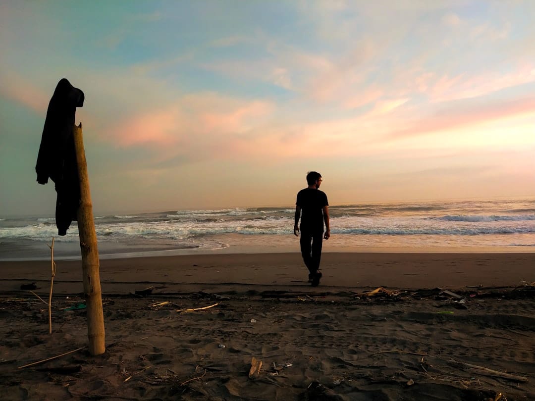 a man standing on top of a sandy beach next to the ocean