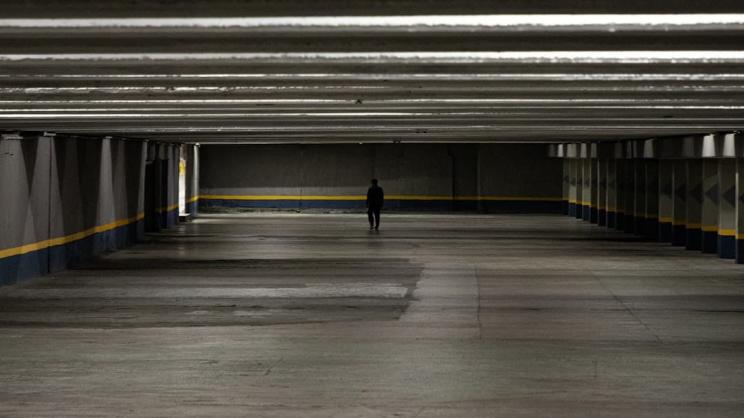 An empty parking garage with a person walking in the distance